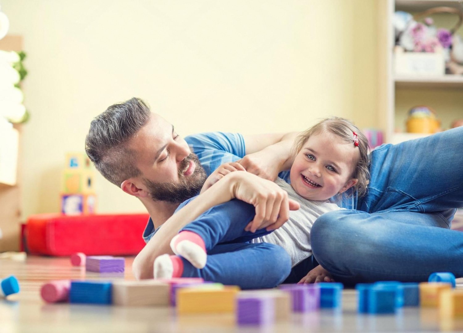 Father and daughter laughing while playing with building block toys indoors