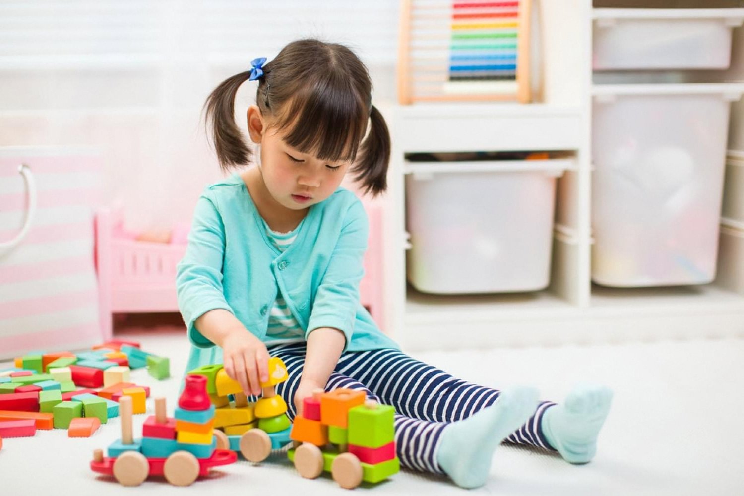 Young girl in the UAE playing with colourful wooden block toys at home