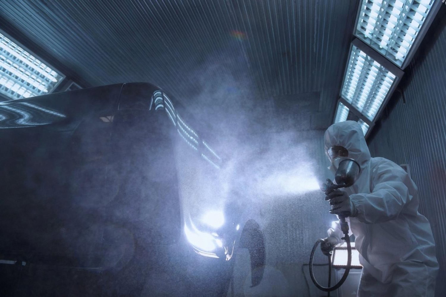 Technician spraying protective coating on a car in a UAE paint booth