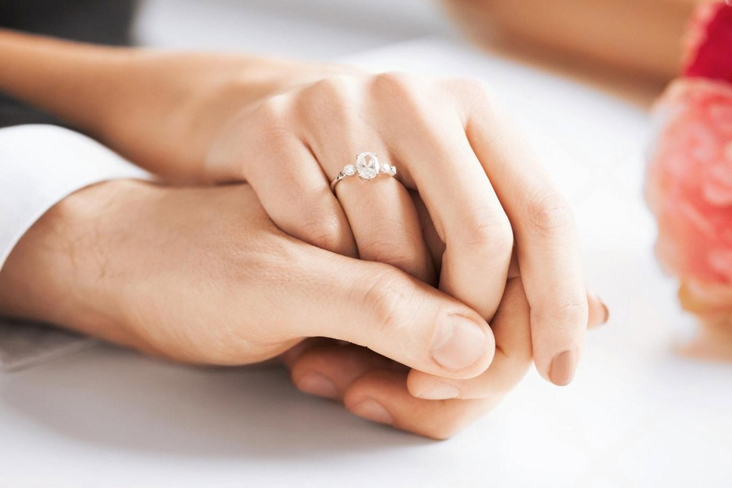 Close-up of a couple holding hands with an engagement ring, symbolising expat marriage in the UAE