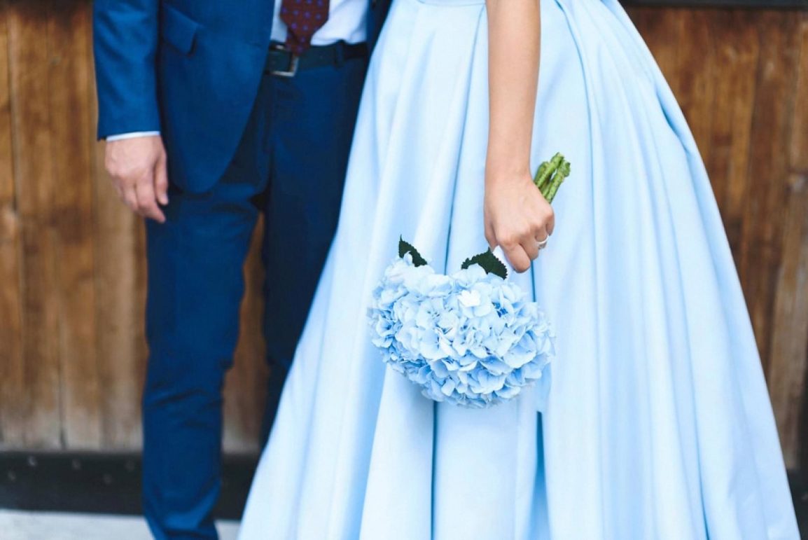 Bride in a pale blue wedding dress with a bouquet standing beside her groom, representing expat weddings in Dubai