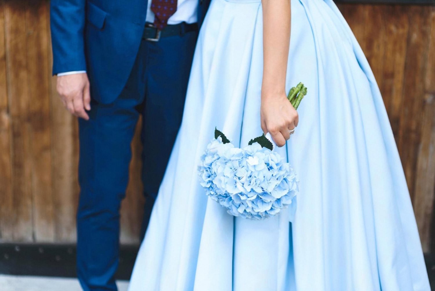 Bride in a pale blue wedding dress with a bouquet standing beside her groom, representing expat weddings in Dubai