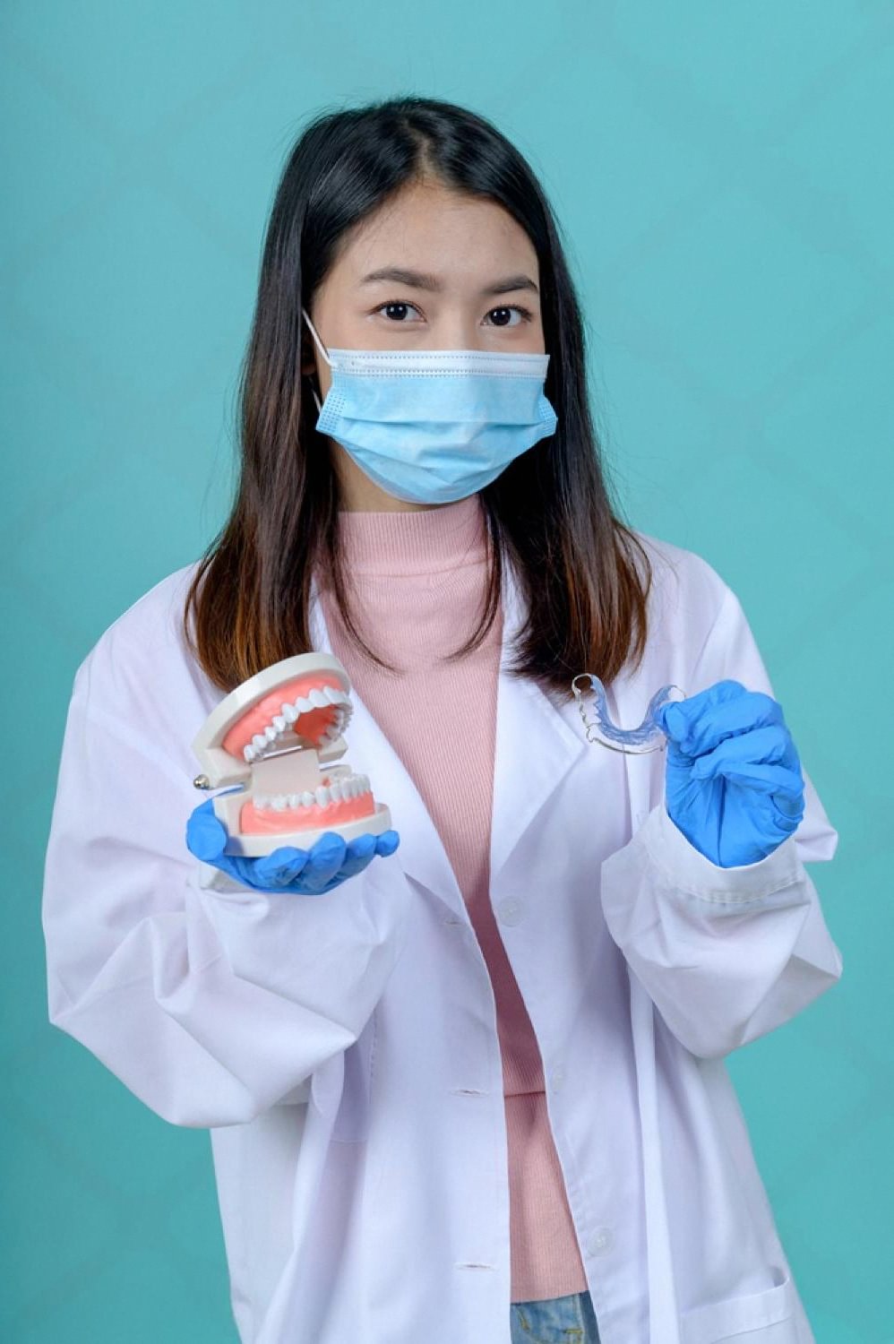 Orthodontist in a UAE clinic holding a dental model and a clear aligner used for braces treatment planning
