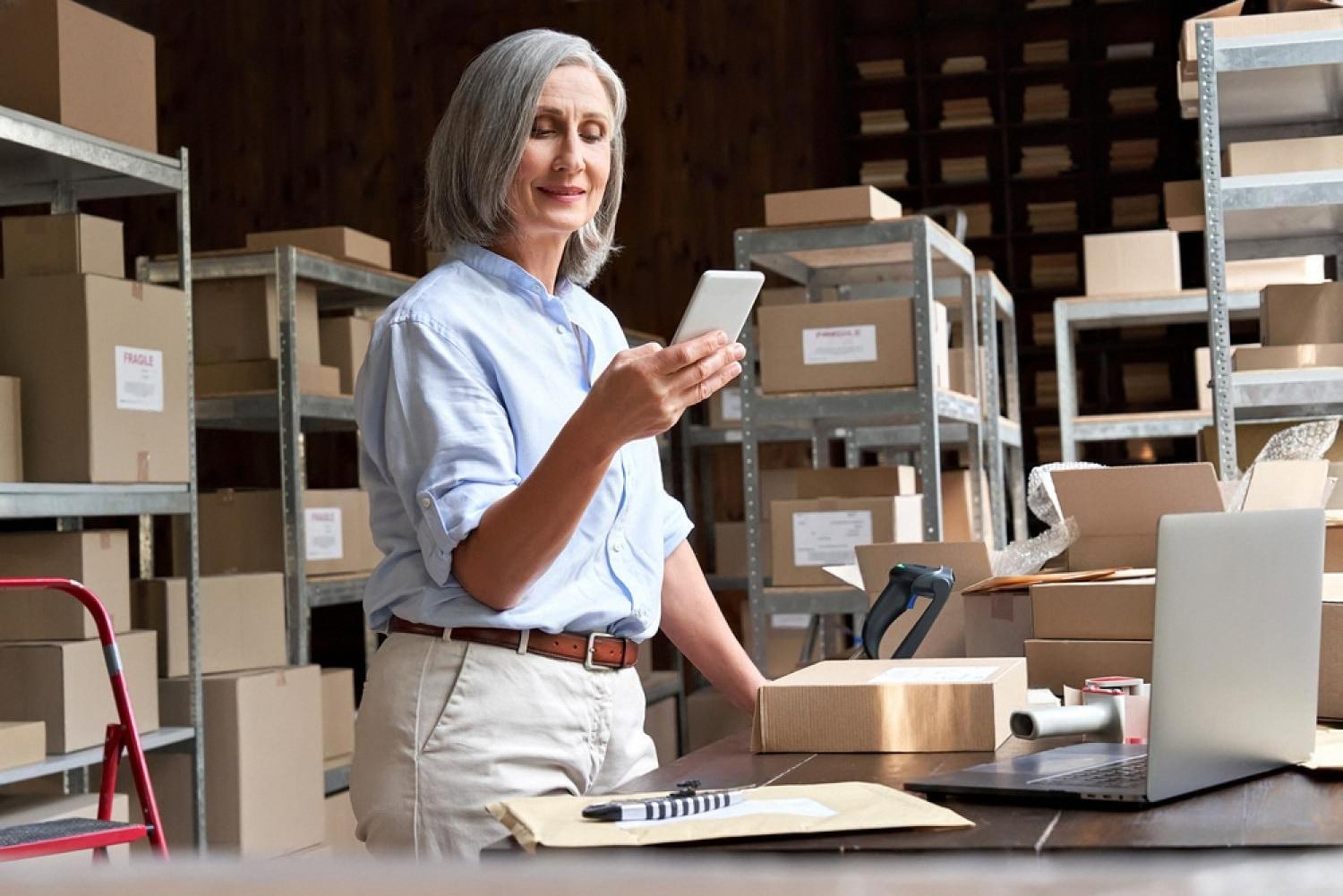 Rental business owner in a UAE warehouse checking her listing on a smartphone